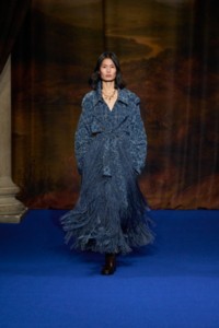 Haojie Qi indossa un trench in misto viscosa con frange e stampa barocca ink blue e stivali Cavalier alti fino alla coscia in pelle treacle brown.