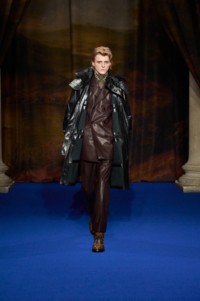 Finn Collins indossa un parka in pelle con finiture in pelliccia sintetica nera, giacca e pantaloni sartoriali in pelle berry purple e stivali Burberry Check in pelle intarsiata nocciola.