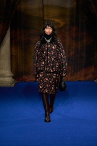 Anugraha Natarajan indossa giacca e gonna con stampa a fiorellini crimson red, abbinata a una borsa in pelle nera e una collana Star Bow smaltata in argento e un anello Shield Segment placcato in oro.